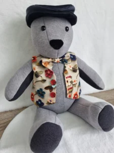 grey memory bear wearing a handmade floral waistcoat and flat cap