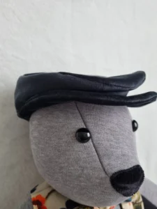 grey handmade memory bear wearing a black flat cap